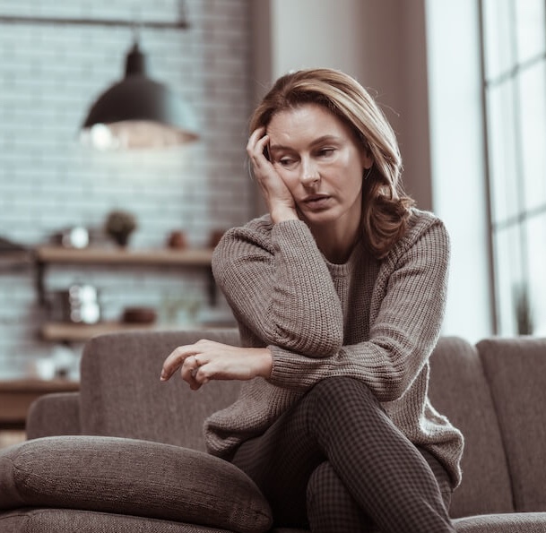 Femme de plus de 40 ans, fatiguée, déprimée, en possible burn-out, qui se tient la tête en regardant dans le vide de côté