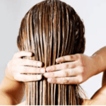 Femme de dos appliquant un soin sur ses cheveux mouillés pour les nourrir