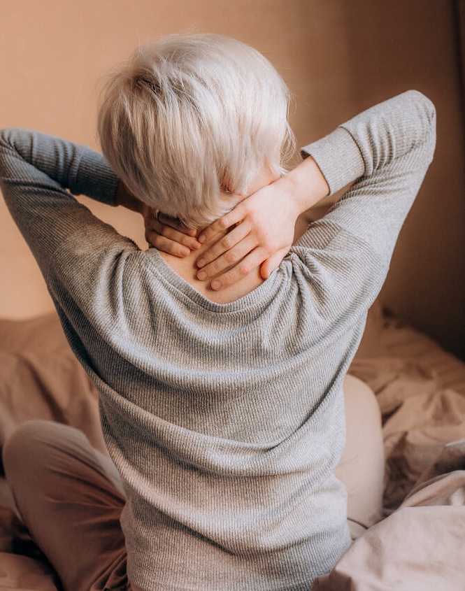 Femme qui a des douleurs cervicales et qui s'étire.