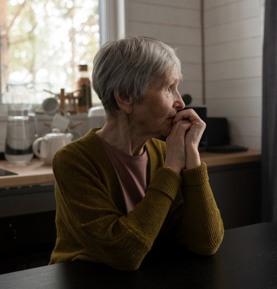 Femme âgée senior triste qui n'a pas le moral et regarde par la fenêtre.