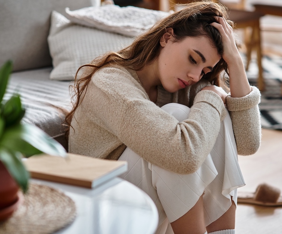 Femme qui regarde de côté en se tenant les cheveux, car elle n'a pas le moral, elle est en dépression.