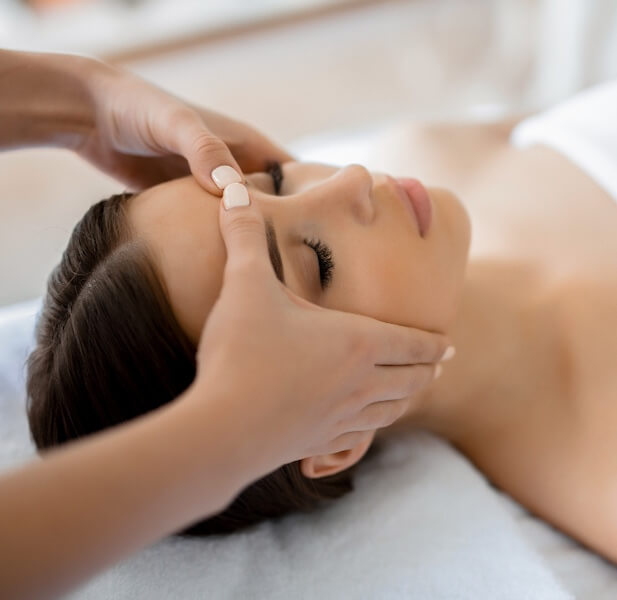 Femme qui se détend et reçoit un massage réflexologie du visage et du crâne