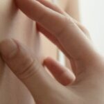 Main d'une femme qui gratte sa peau sur le haut de son buste