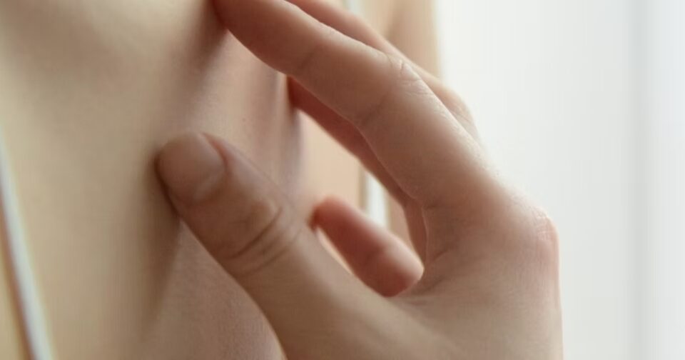 Main d'une femme qui gratte sa peau sur le haut de son buste