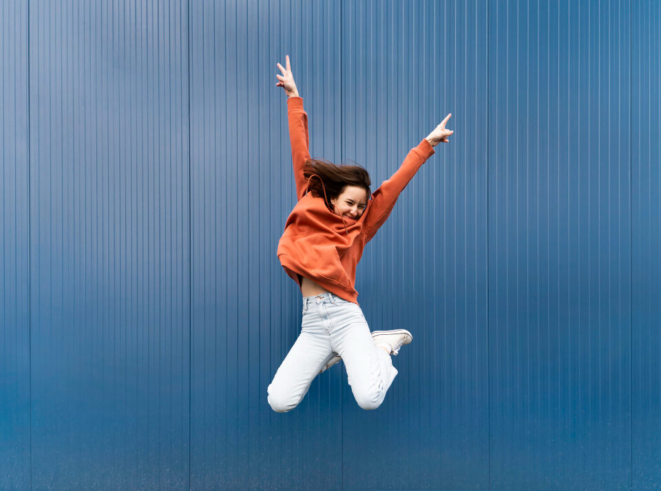 Femme dynamique et joyeuse qui saute bras en l'air